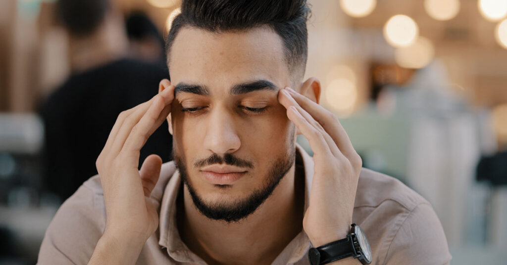 Man thinking, eyes closed, fingers on his temples.