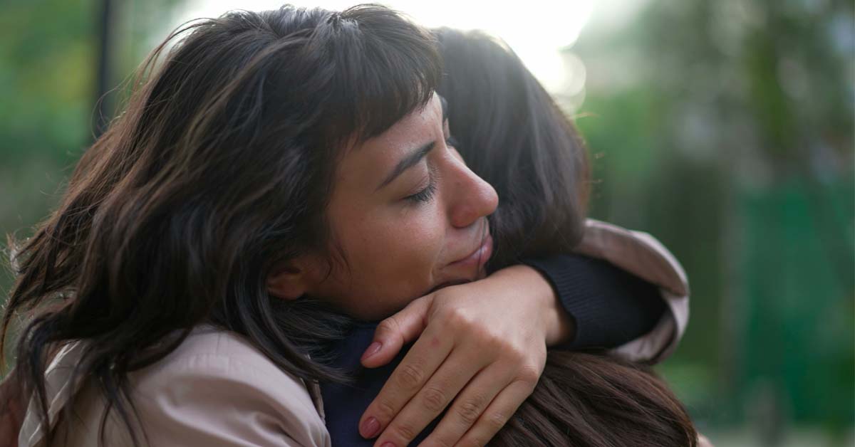 woman hugging woman in supportive embrace