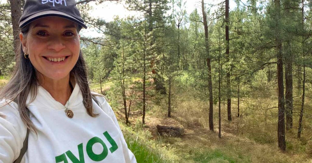 Author hiking in Colorado with a hat that says "hope" and a hoodie that says "love."